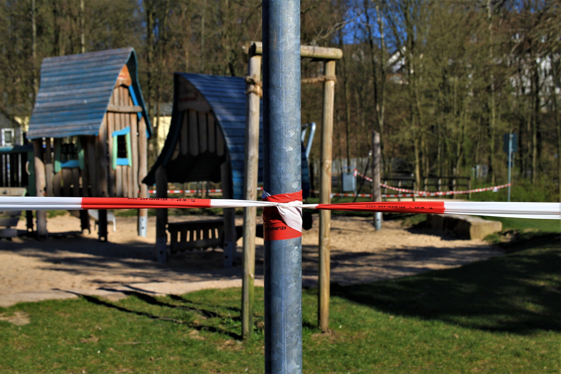 Ein Spielplatz ist mit rot-weißem Flatterband abgesperrt.