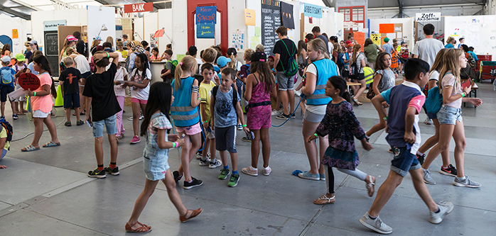 Viele Kinder laufen kreuz und quer durch ein großes Veranstaltungszelt.